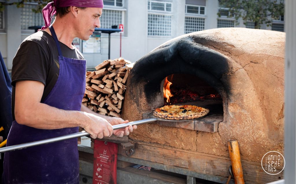 Le restaurateur met une pizza dans un four à pizza fait main